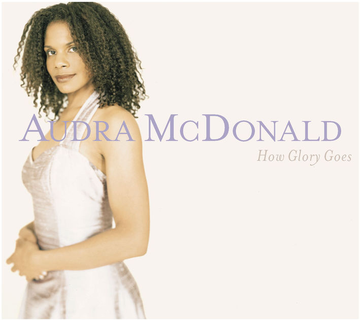 The cover for Audra McDonald's album "How Glory Goes" featuring Audra in a white dress smiling and posing in front of a white background.